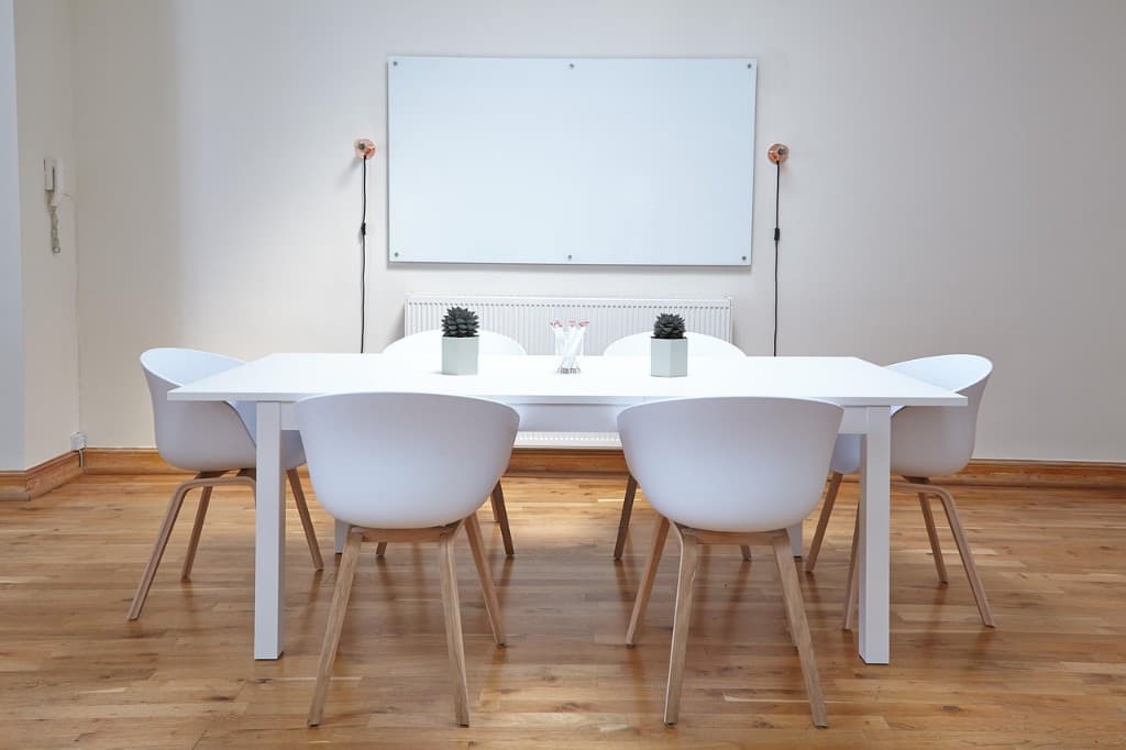 Bright shared meeting space — table, chairs, and whiteboard for the 12-week program